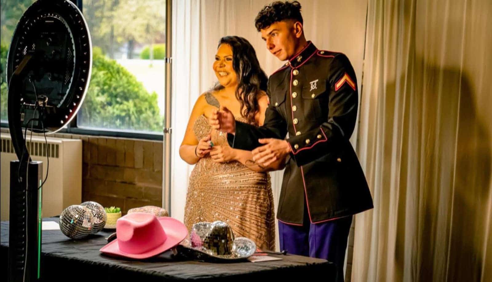 Couple posing at the booth in dress blues and a gold gown